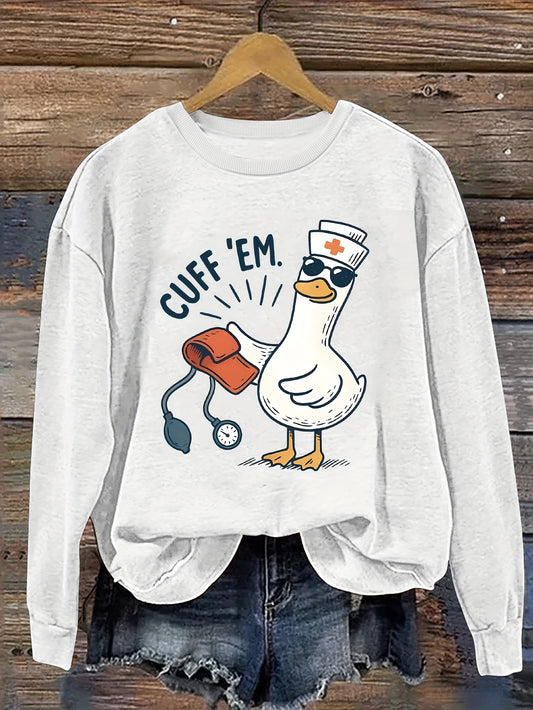 A cozy pink “Silly Goose” nurse sweatshirt featuring a cute duckling and bold CUFF ’EM slogan, perfect for winter shifts and everyday scrubs style.