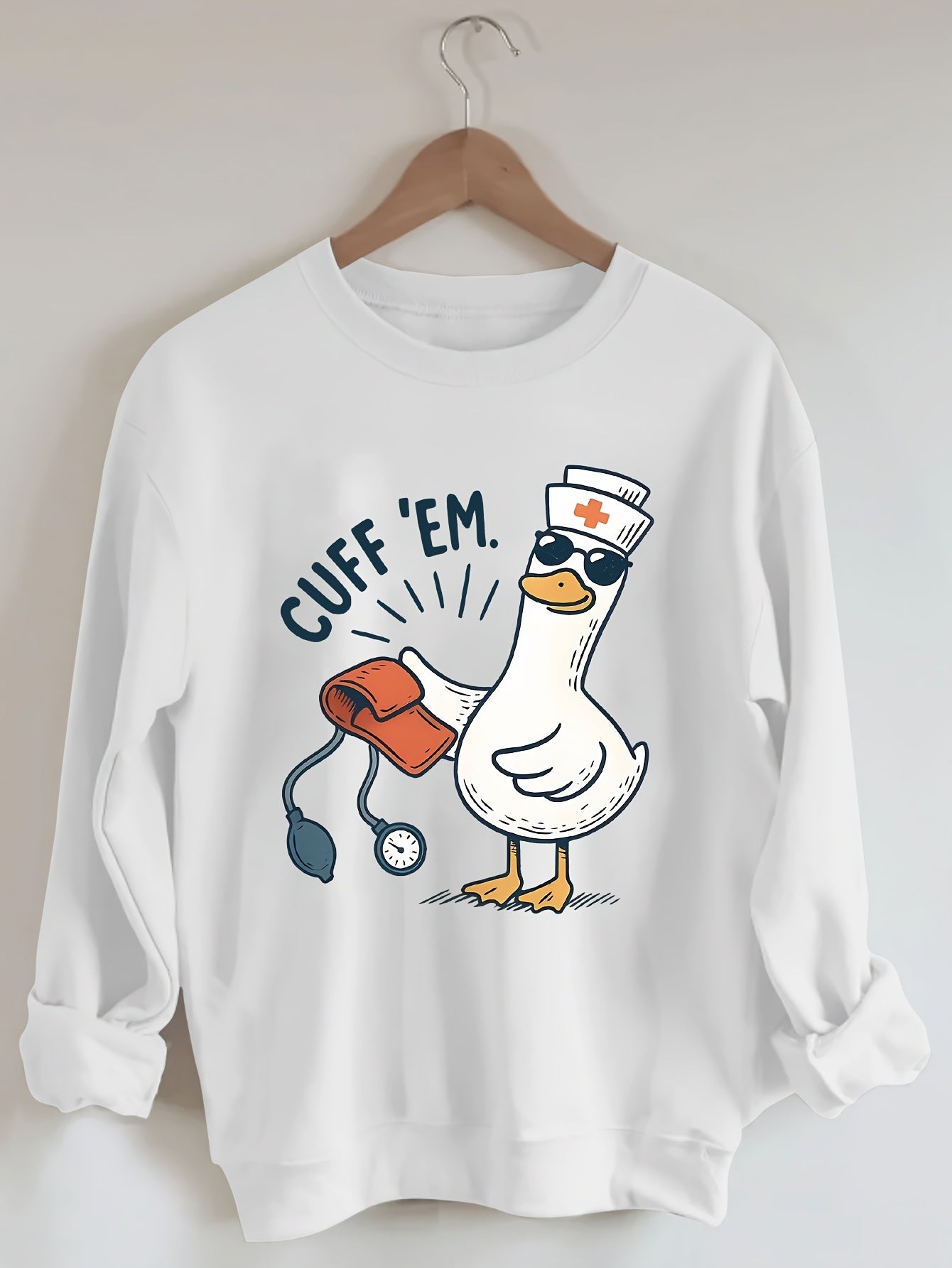A cozy pink “Silly Goose” nurse sweatshirt featuring a cute duckling and bold CUFF ’EM slogan, perfect for winter shifts and everyday scrubs style.